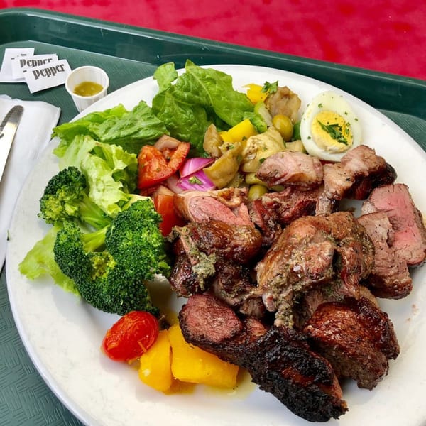 Pampas Grill plate with grilled steak, broccoli, lettuce, tomatoes, peppers, and a hard-boiled egg.