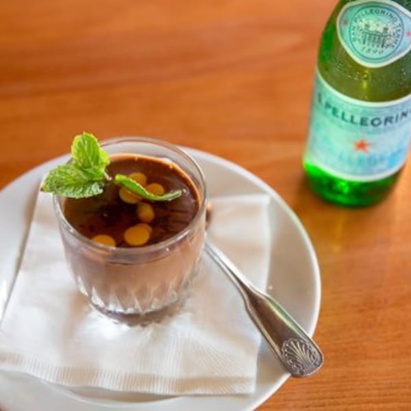 Brazilian chocolate dessert with mint and yellow candies, next to a San Pellegrino bottle.