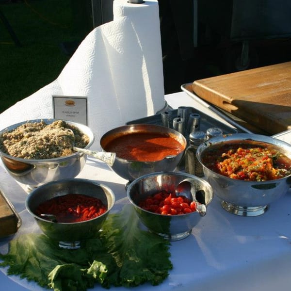 A buffet spread of Brazilian farinha, sauces, and salsa in silver bowls on a white tablecloth.