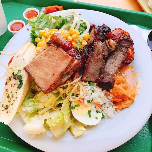 A plate of Pampas Grill's Brazilian barbecue with various meats, rice, pasta, salad, and garlic bread.