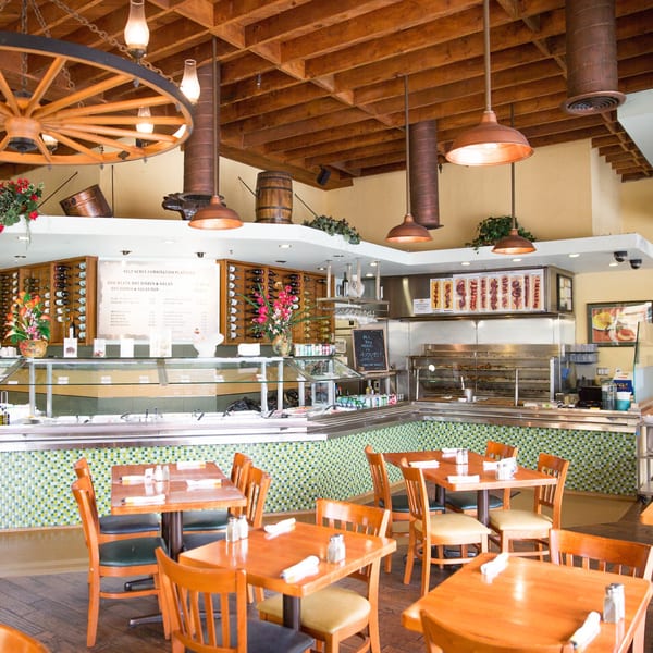 Pampas Grill interior with a buffet, dining tables, wooden ceiling, and wagon wheel chandelier.